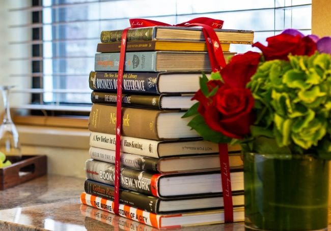 Stack of hand selected books and floral arrangement.
