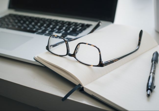 Table with laptop, glasses and notebook