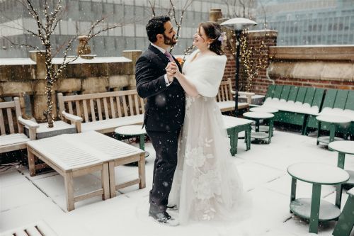 The New Mr. & Mrs. enjoying a picturesque snowfall as the perfect touch to our rooftop terrace photo spot. Photo by: Lauren Spinelli Photography